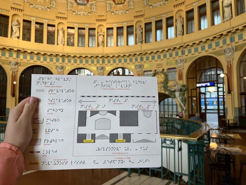 První grafický list hmatáku č. 16 Praha hlavní nádraží, na pozadí Fantova kavárna.